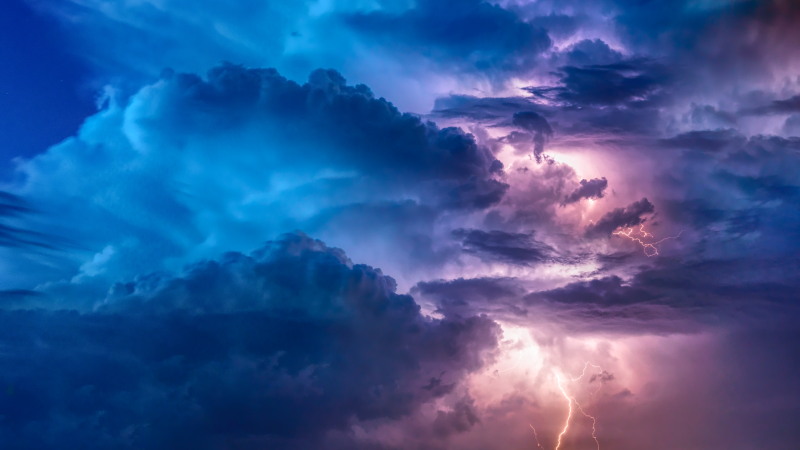 Blue and purple sky with a mass of clouds and lighting bolts