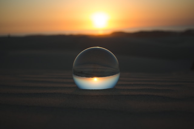Inverted view of sunset through a glass sphere lain on the sand.